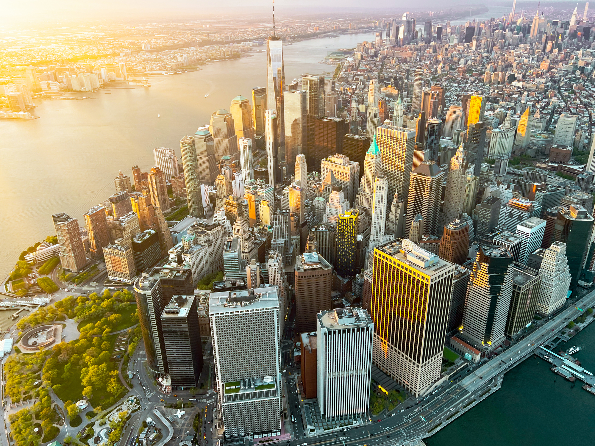 An aerial view of the New York City skyline at sunset, with the Hudson River visible.