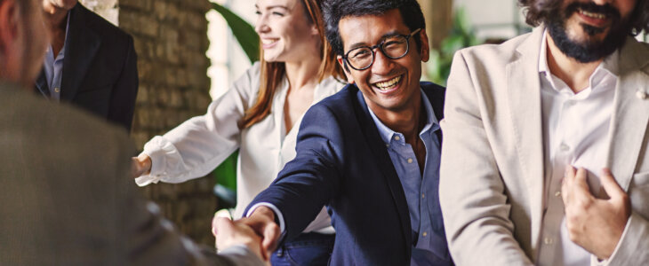 Group of diverse professionals celebrating with a handshake at a corporate event, embodying teamwork and achievement.