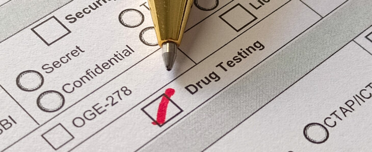 A close-up of a pen checking the "Drug Testing" box on a job application.
