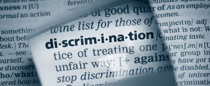 A magnifying glass on a dictionary page showing the word 'discrimination'.