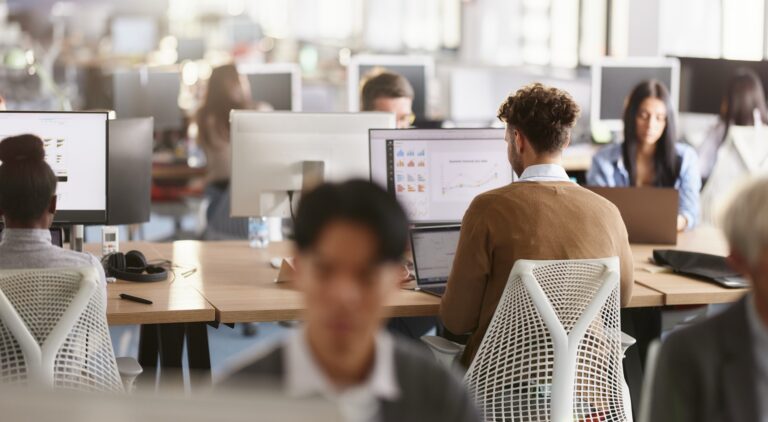 Office workers in an open plan office working on computers.