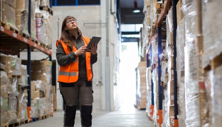 A warehouse worker checks stock on a tablet.