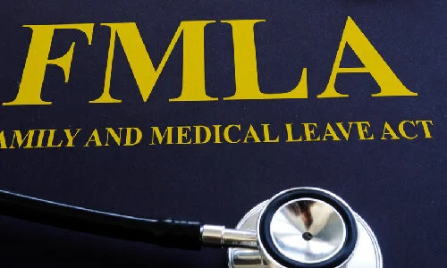 FMLA Family and Medical Leave Act booklet with stethoscope and pen on desk.