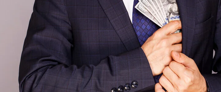 Businessman putting money in suit jacket pocket