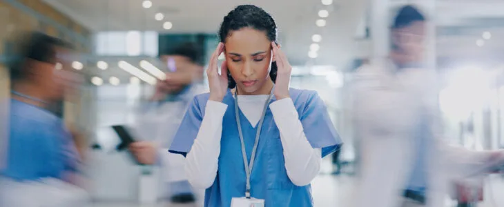 Nurse, woman and headache in hospital with stress of medical mistake, overworked and burnout. Motion blur, healthcare worker and migraine in busy clinic with fatigue, crisis and frustrated for chaos